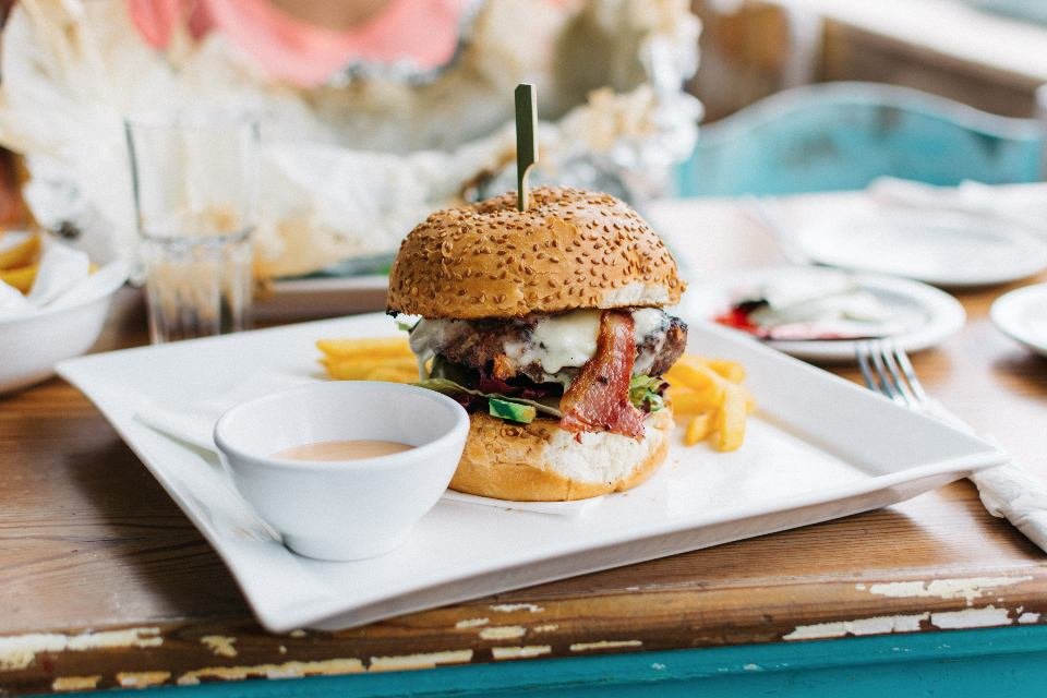Burger maison servi avec des frites sur une assiette blanche