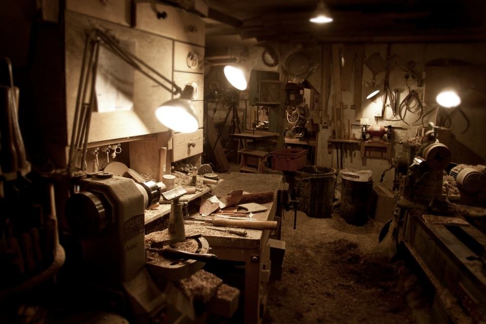 Atelier de menuiserie éclairé par des lampes d'établi, tour à bois au premier plan